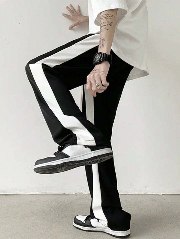 Black unisex track pants with wide white side stripe, cuffed hem, stylestitch